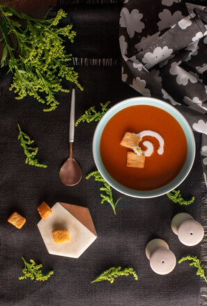 A bowl of soup with croutons and a swirl of cream on a dark cloth. - Apple Country Resorts - A Vegetarian Place (Manali)