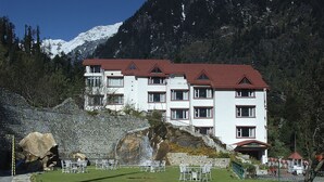 A hotel with a red roof, multiple floors, and a mountainous backdrop.