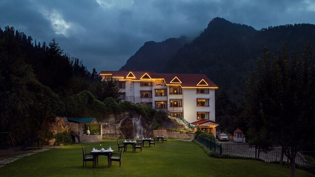 A hotel with a red roof, multiple floors, and a well-maintained lawn with tables and chairs.
