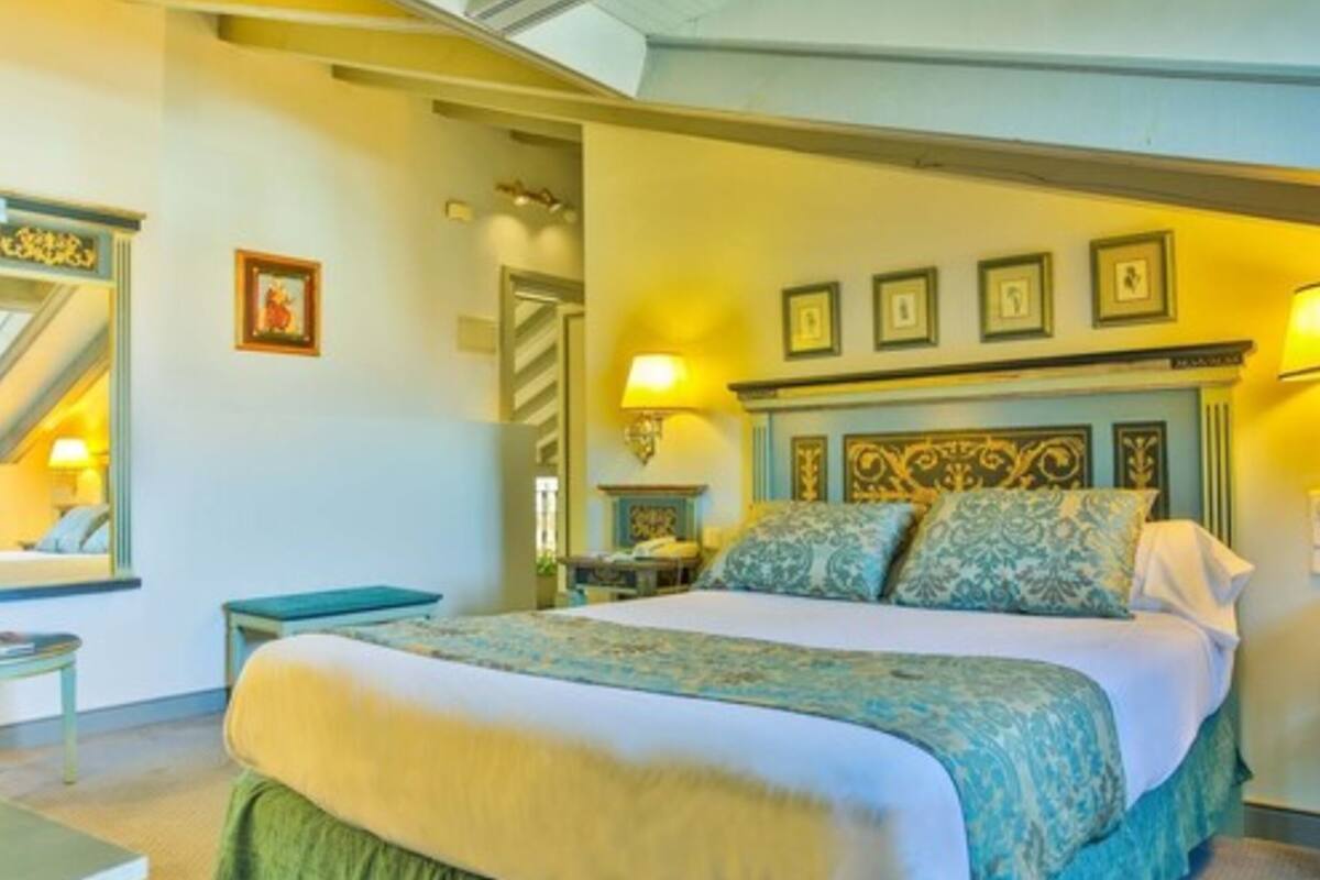 Une chambre d’hôtel avec un grand lit, une table de chevet, une lampe et un tableau encadré au mur.