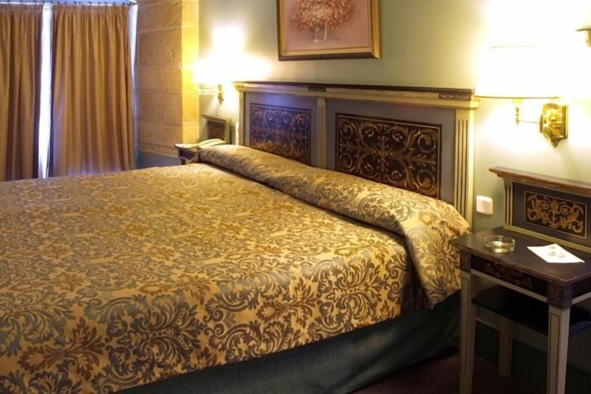 Ein Hotelzimmer mit einem großen Bett, einem Nachttisch und einer Wandlampe.