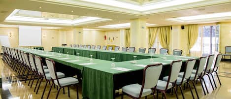 A conference room with a long table, chairs, and a projector screen.
