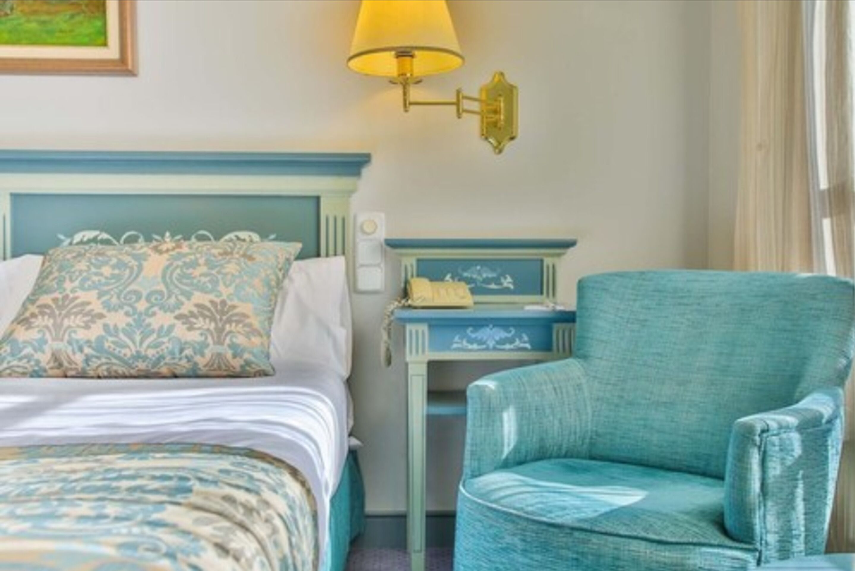 A hotel room with a bed, a chair, a nightstand, and a lamp.