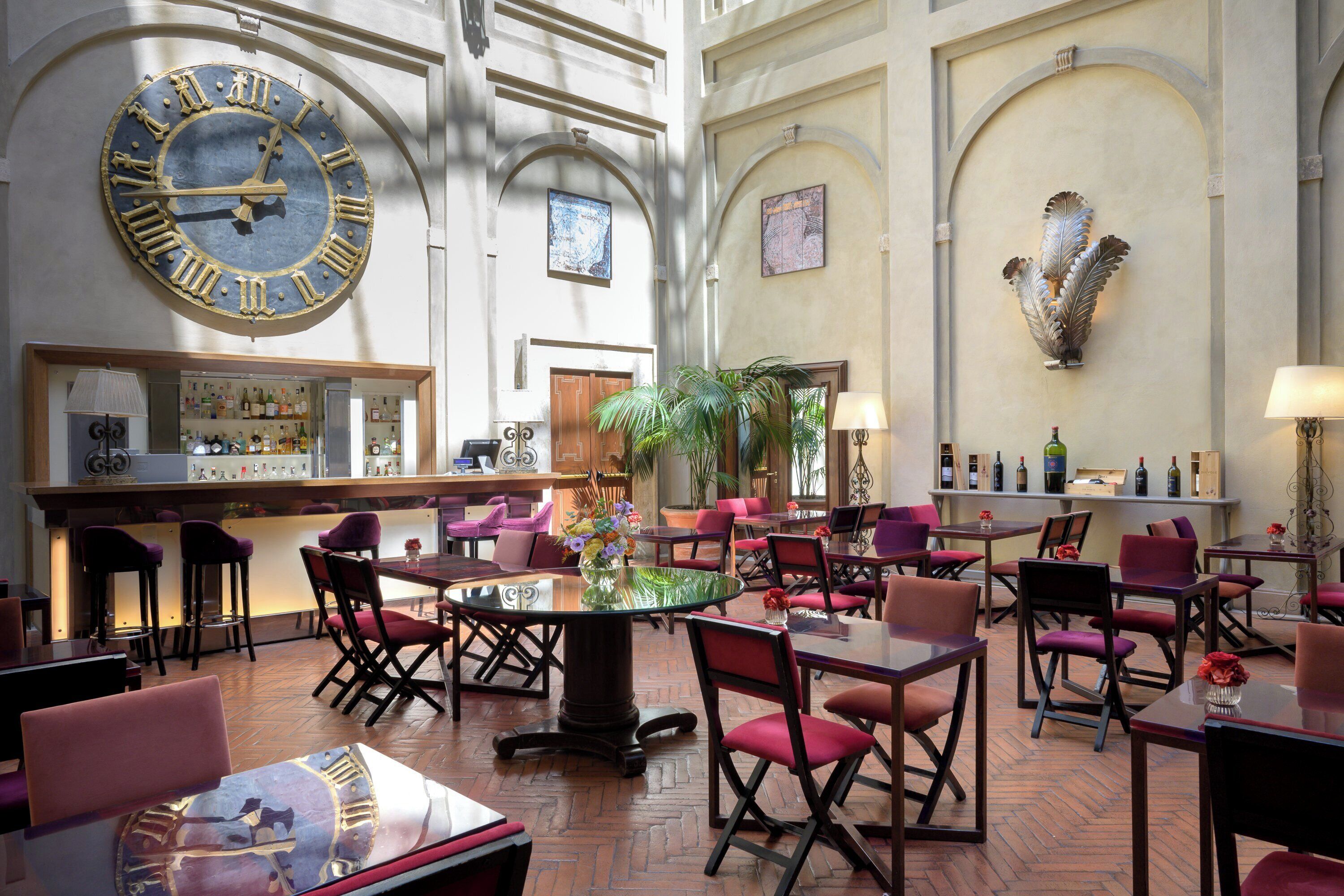A spacious lobby with a large wall clock, multiple seating areas, and a bar.