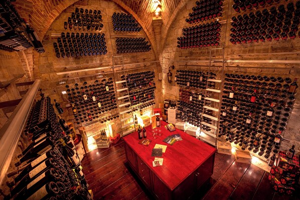 Una bodega con numerosas botellas organizadas en estanterías y cavas.