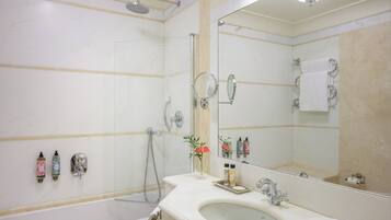 Ein Badezimmer mit einer Badewanne, einem Waschbecken, einem Spiegel und Pflegeprodukten an der Wand.