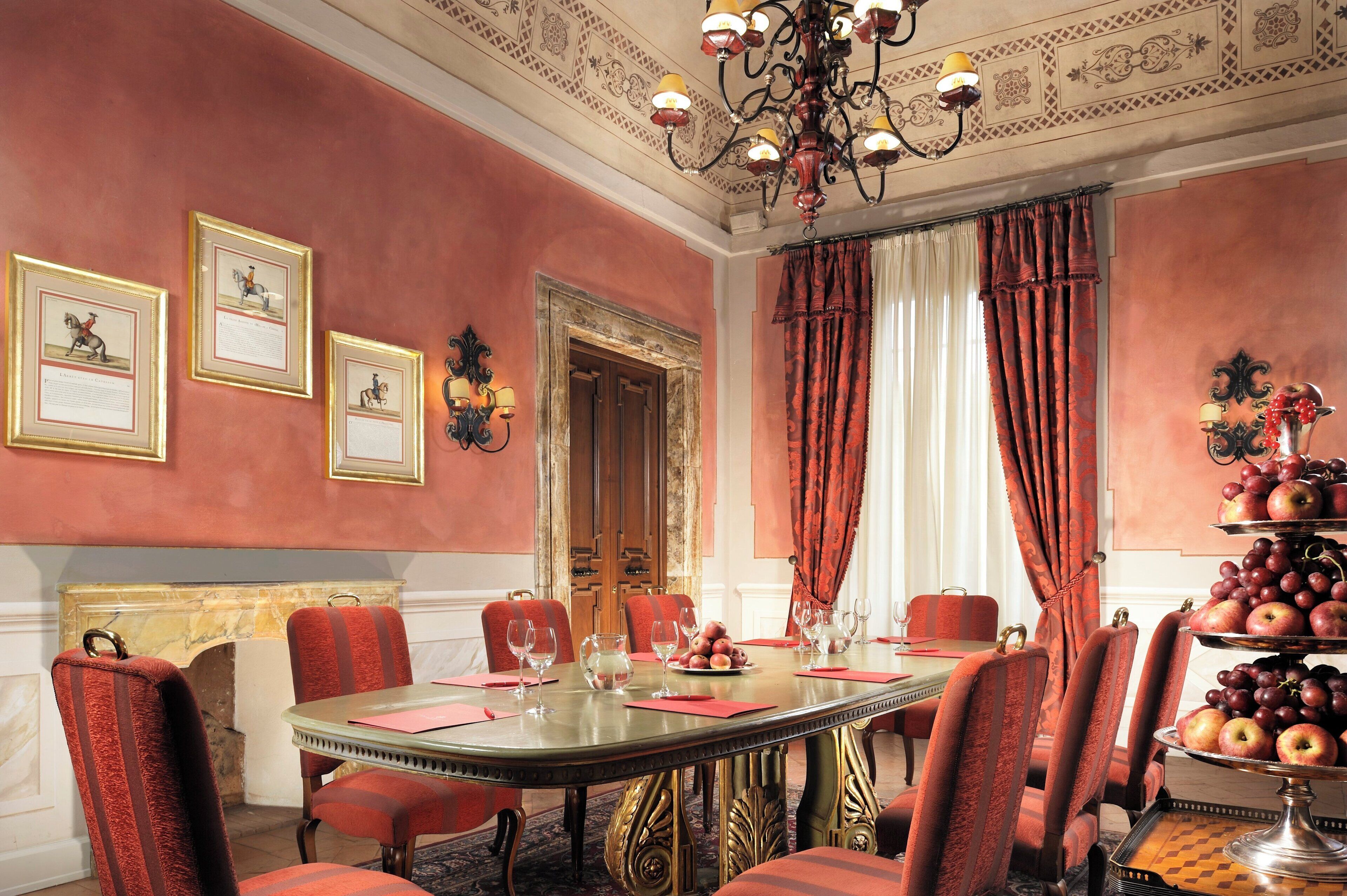 A formal dining room with a large table, red upholstered chairs, and a chandelier.