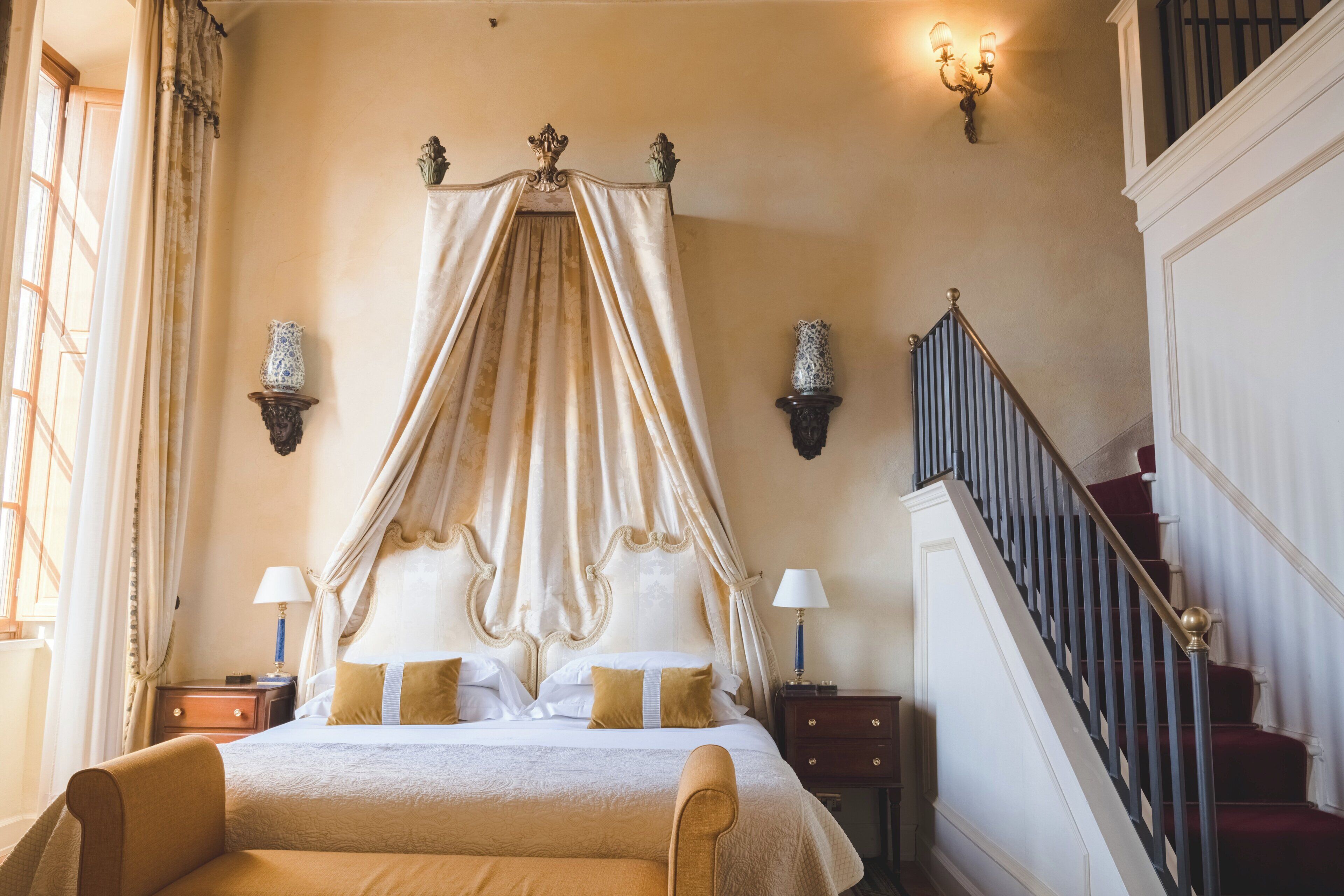 Une chambre à coucher avec un lit à baldaquin, un escalier et des appliques murales.