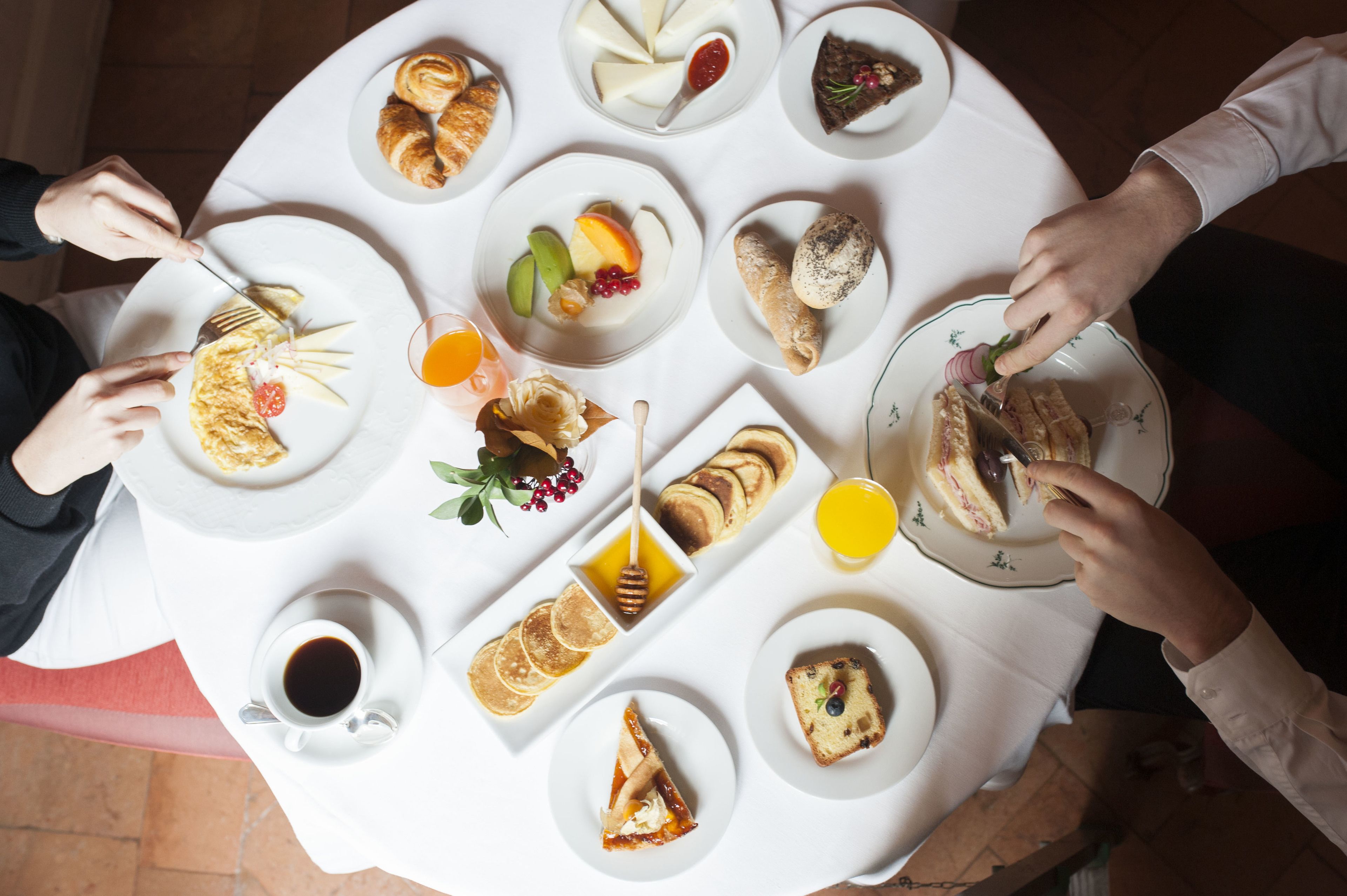 A round table with various breakfast items including pastries, fruits, and beverages.