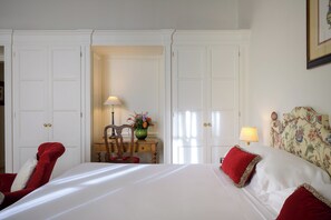 A hotel room with a large bed, a chair, a desk, and a lamp. - Grand Hotel Continental Siena – Starhotels Collezione (Siena)