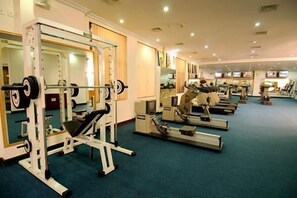A gym with various exercise equipment, including a squat rack and treadmills. - Golden Palms Hotel And Spa (Bengaluru)