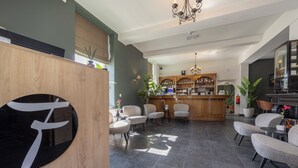 Una zona de bar moderna con mostrador de madera, taburetes y una araña.