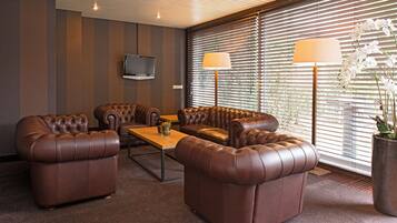 A modern living room with leather sofas, a coffee table, and a TV mounted on the wall.