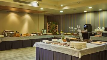 A buffet setup with various food items and a coffee station in a hotel room.