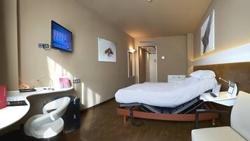 Una habitación de hotel con cama, escritorio, silla y televisor.
