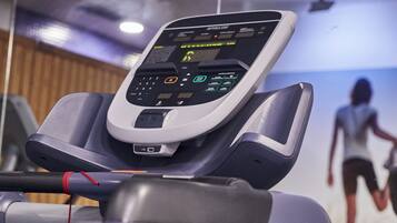 Una cinta de correr con pantalla digital y un cable rojo.