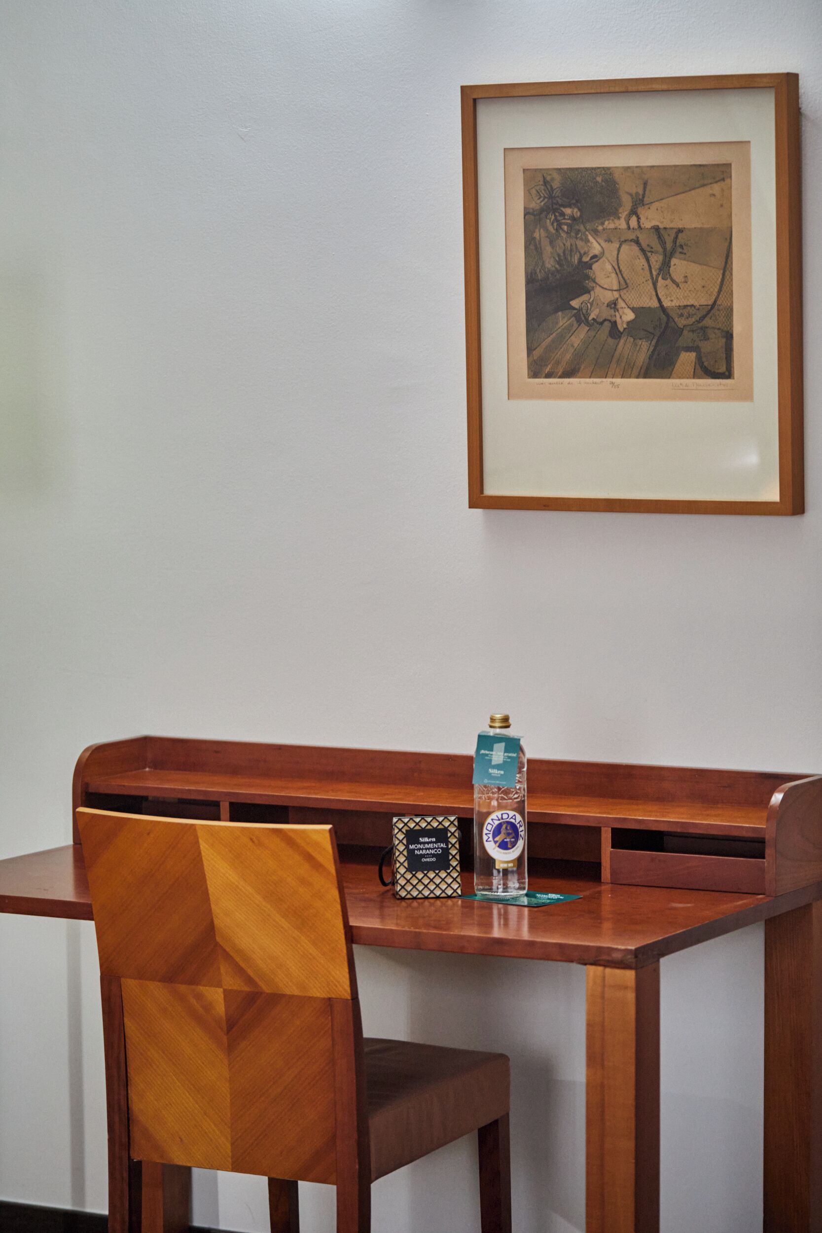 Una mesa de comedor de madera con una obra enmarcada encima.