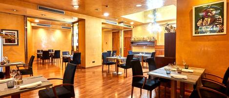 A restaurant with wooden flooring, tables set for dining, and a bar area.