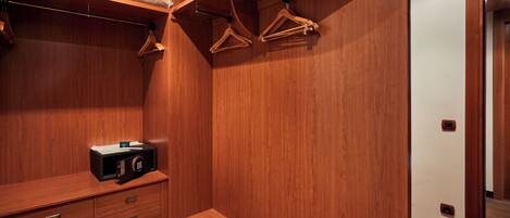 A wooden walk-in closet with a bench, a microwave, and wooden hangers on a curved shelf.