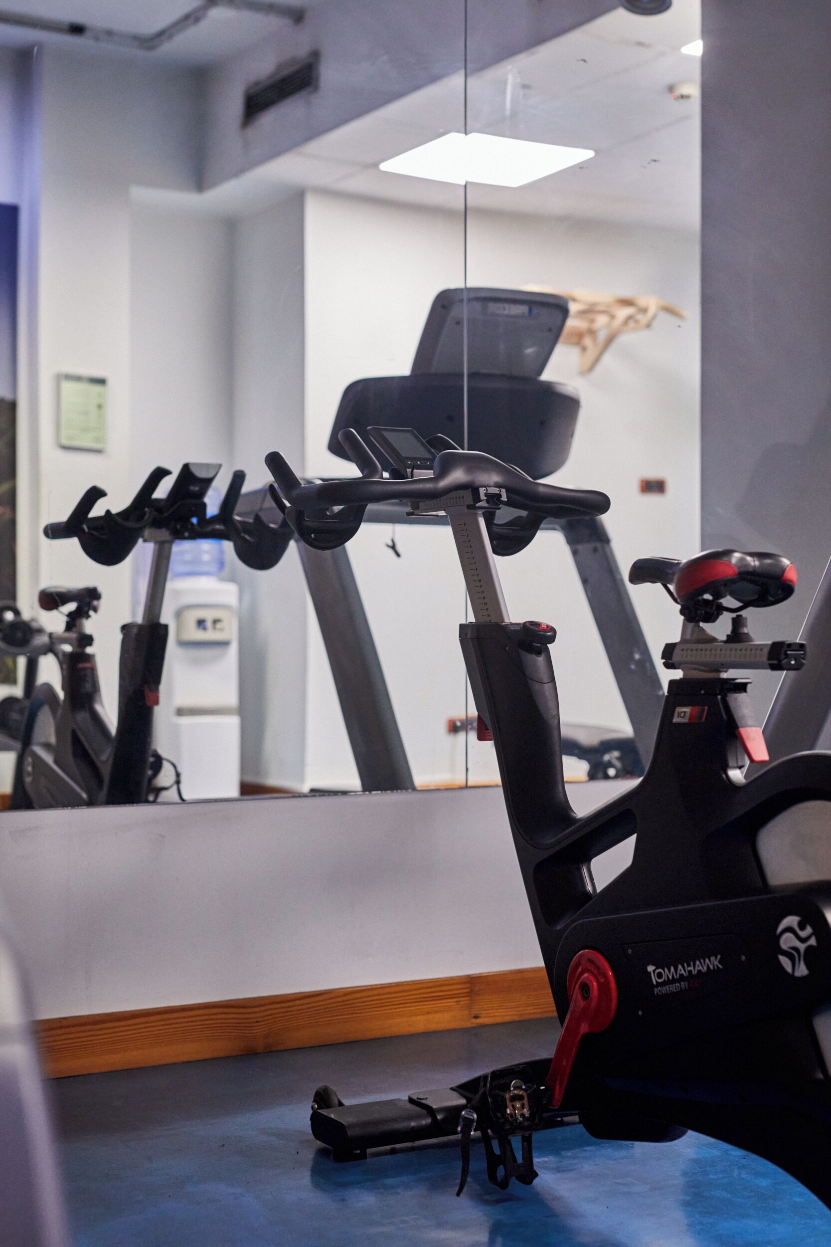 Bicicleta ergométrica numa academia, com um espelho refletindo o ambiente.