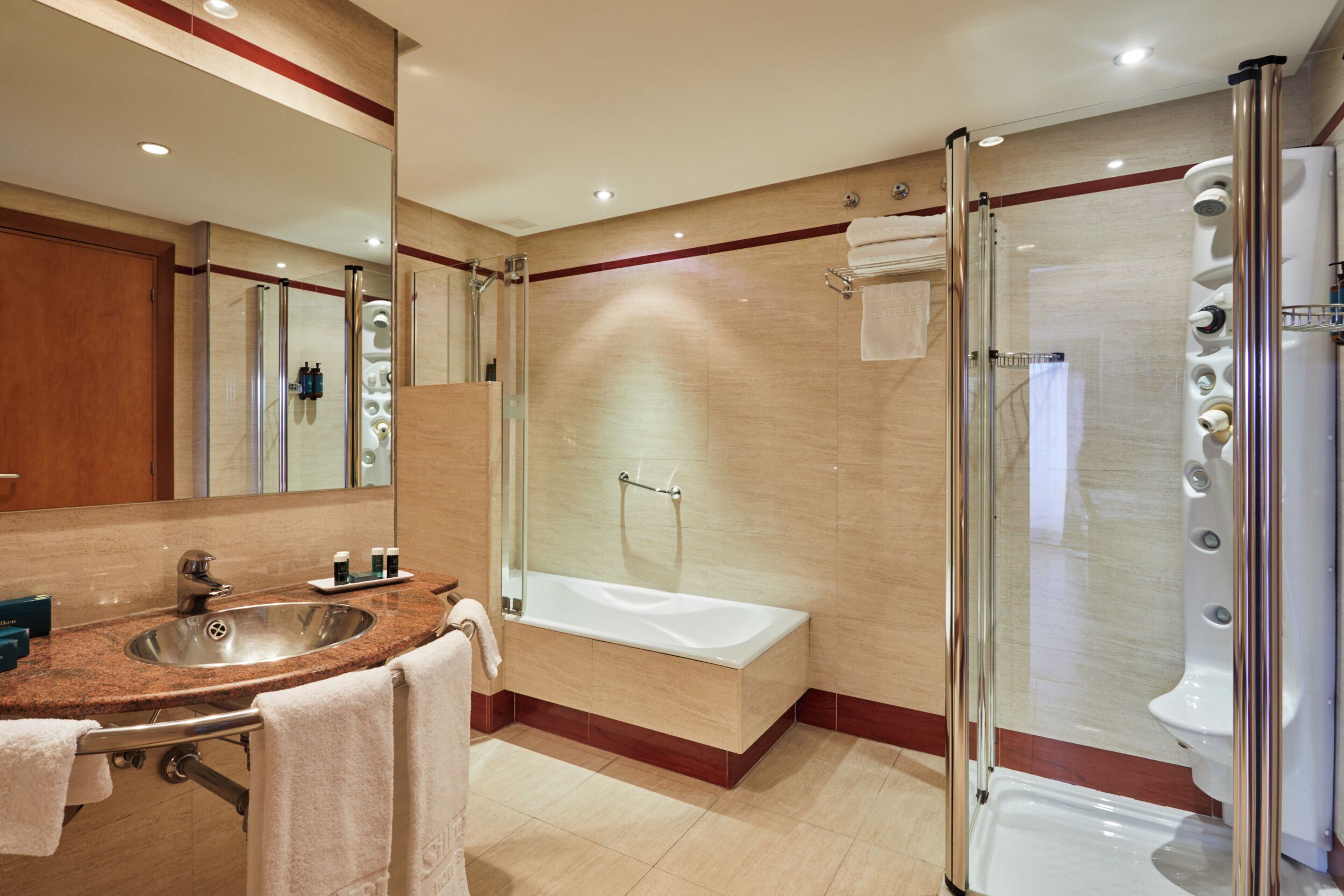 Une salle de bain moderne équipée d’un lavabo, d’un miroir, d’une baignoire et d’une douche à parois de verre.