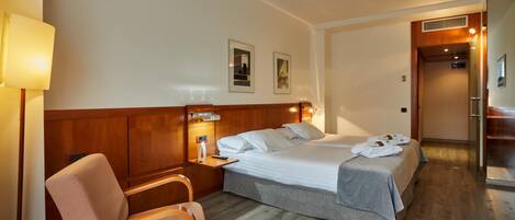 A hotel room with a bed, a chair, a nightstand, and a lamp.