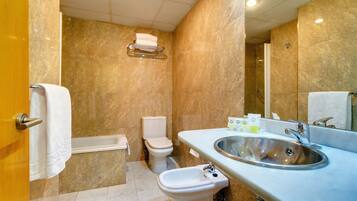 Ein Badezimmer mit Marmorwand, einem Waschbecken, einem Bidet und einer Toilette.