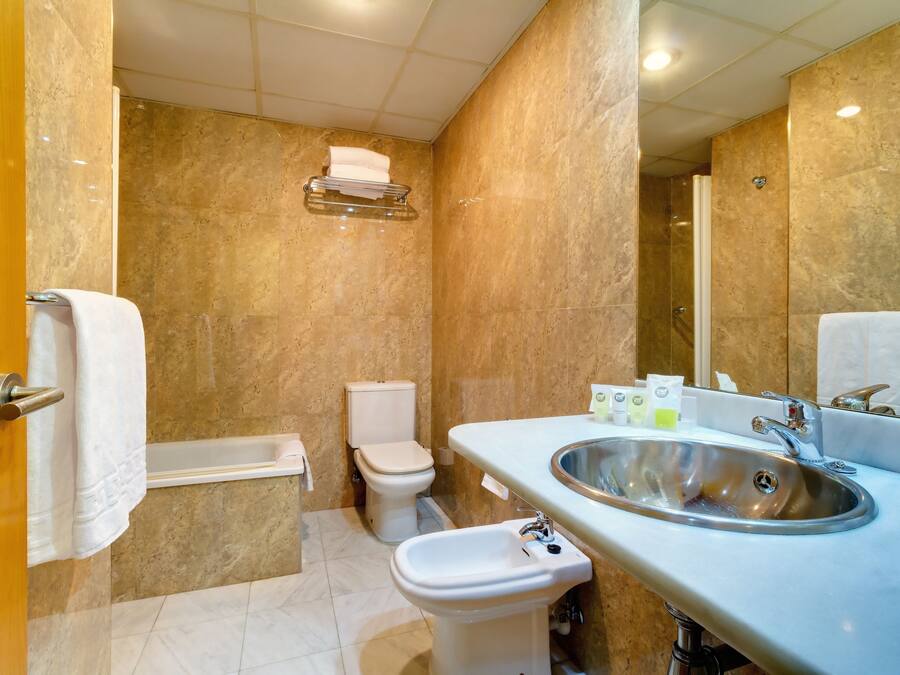 Ein Badezimmer mit Marmorwand, einem Waschbecken, einem Bidet und einer Toilette.