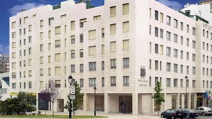 Un hotel de varios pisos con fachada simétrica, numerosas ventanas y una entrada central.