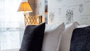 A bed with black and white pillows, a gold lamp, and a patterned wallpaper. - Villa Lutece Port Royal (Paris)