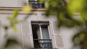 A building with multiple windows, some with shutters, and balconies with wrought iron railings. - Villa Lutece Port Royal (Paris)