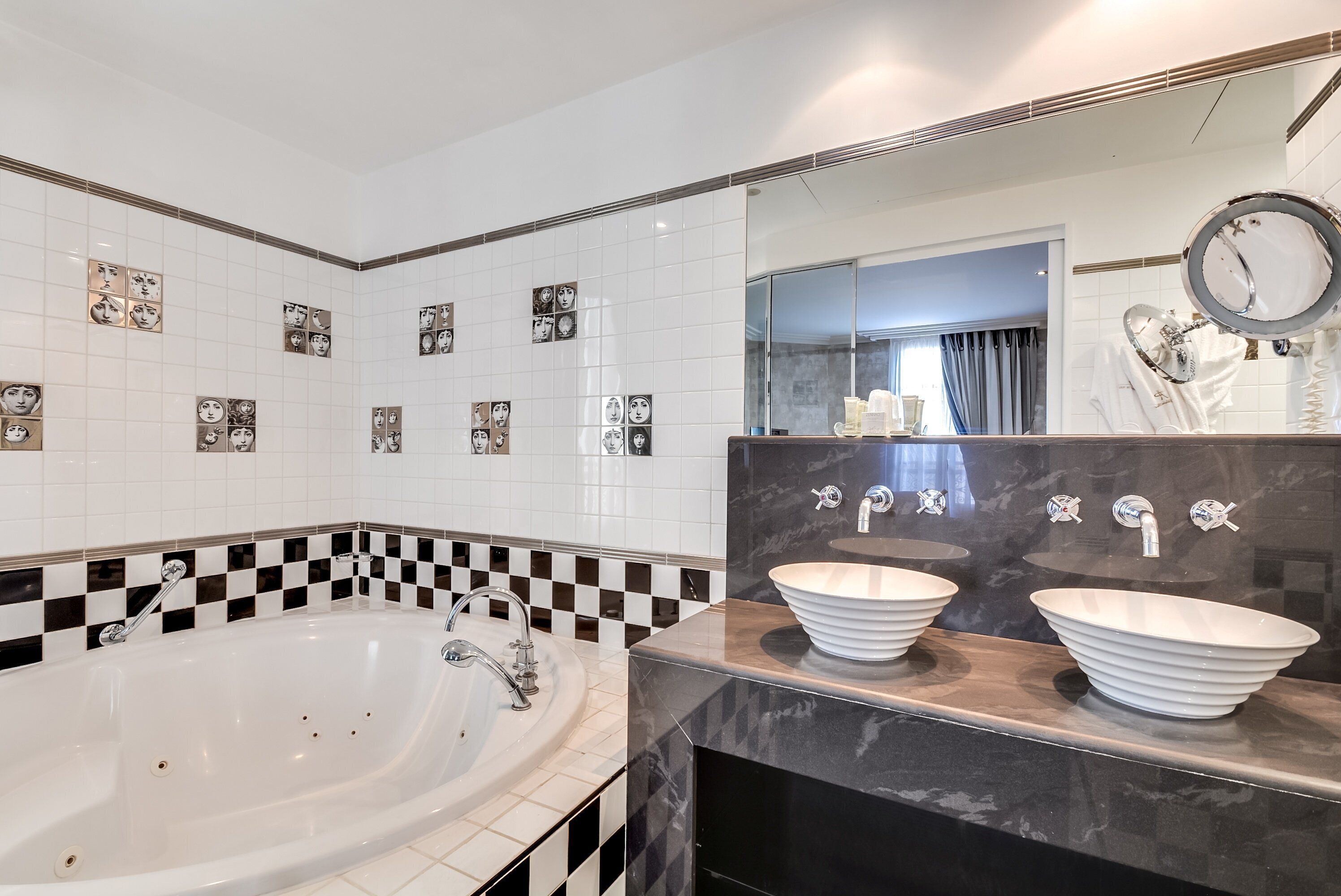 Een badkamer met een groot bad, twee wastafels en een spiegel.
