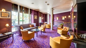 A hotel lobby with purple walls, yellow chairs, a black sofa, and a patterned carpet. - Villa Lutece Port Royal (Paris)