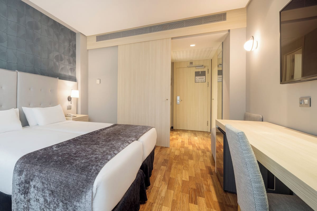 Een moderne hotelkamer met een groot bed, een nachtkastje, een bureau en een spiegel.