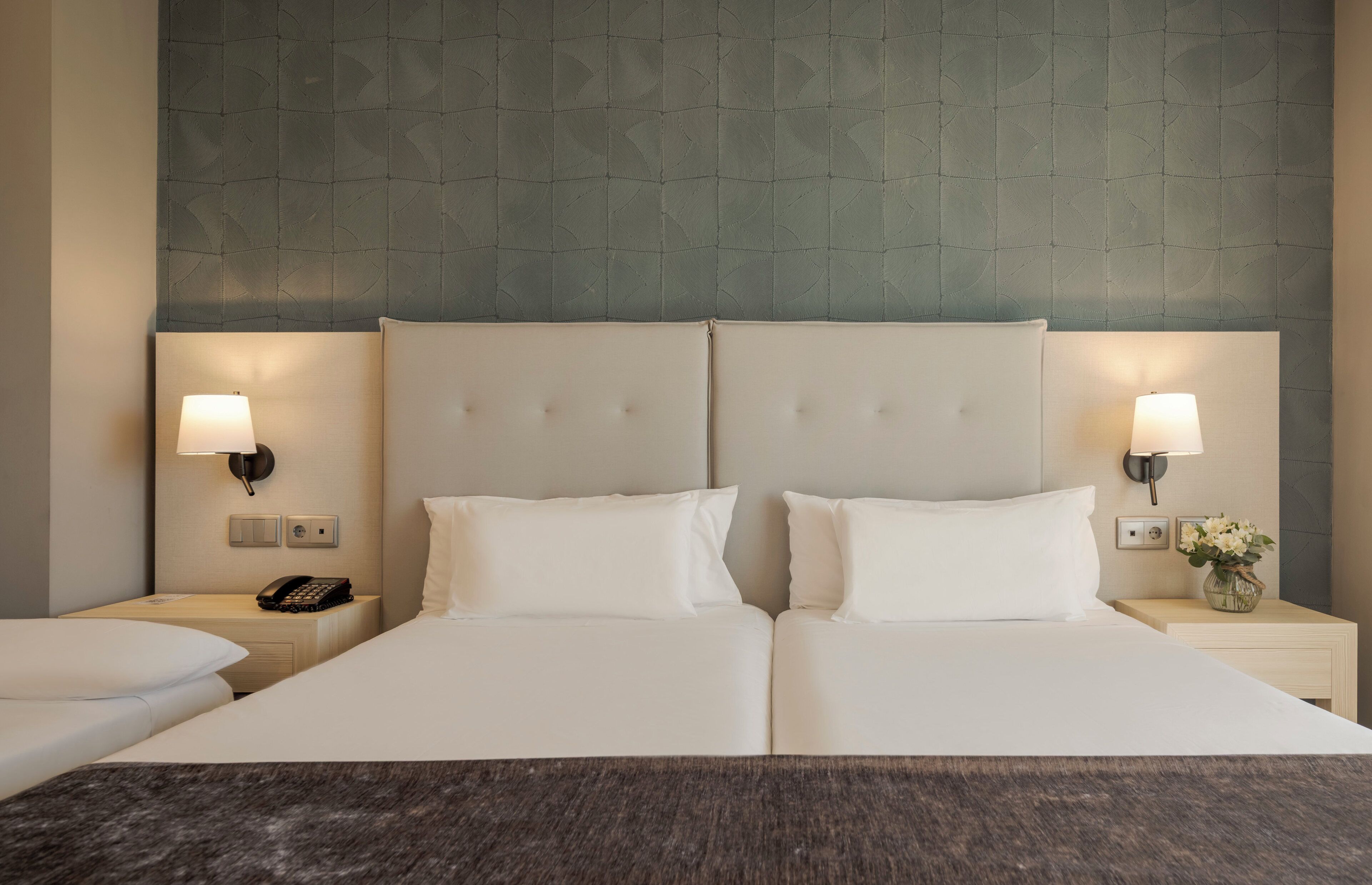 Ein Doppelbett mit zwei weißen Kissen, ein Nachttisch mit Lampe und Telefon.