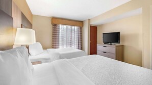 A hotel room with two beds, a TV, a lamp, and a window with curtains. - Quality Suites (Indianapolis)