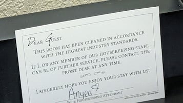 A handwritten note on a card placed in a black holder, likely in a hotel room.