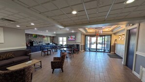 A spacious lobby with a bar area, seating arrangements, and a fireplace. - Quality Suites (Indianapolis)