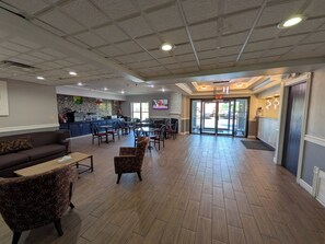 A spacious lobby with a bar area, seating arrangements, and a fireplace. - Quality Suites (Indianapolis)