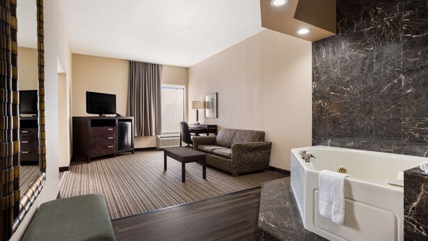 Een hotelkamer met een groot bad, een bank, een televisie en een bureau.