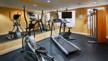 A gym with treadmills, elliptical machines, and a mirrored wall.