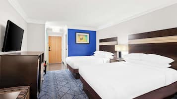 Habitación de hotel con una cama grande, televisión, escritorio y una pared decorada en azul.