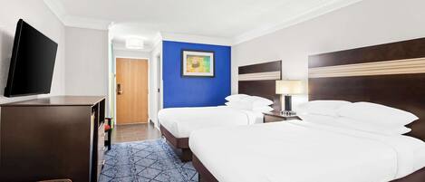 Habitación de hotel con una cama grande, televisión, escritorio y una pared decorada en azul.