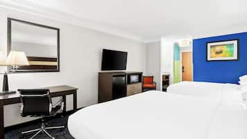 A hotel room with a large bed, a desk with a chair, a TV, and a painting on the wall.