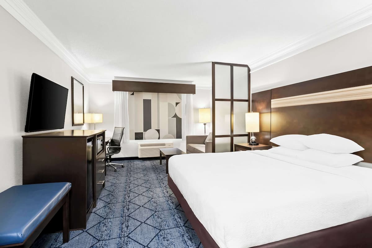 A hotel room with a bed, desk, chair, and a television.