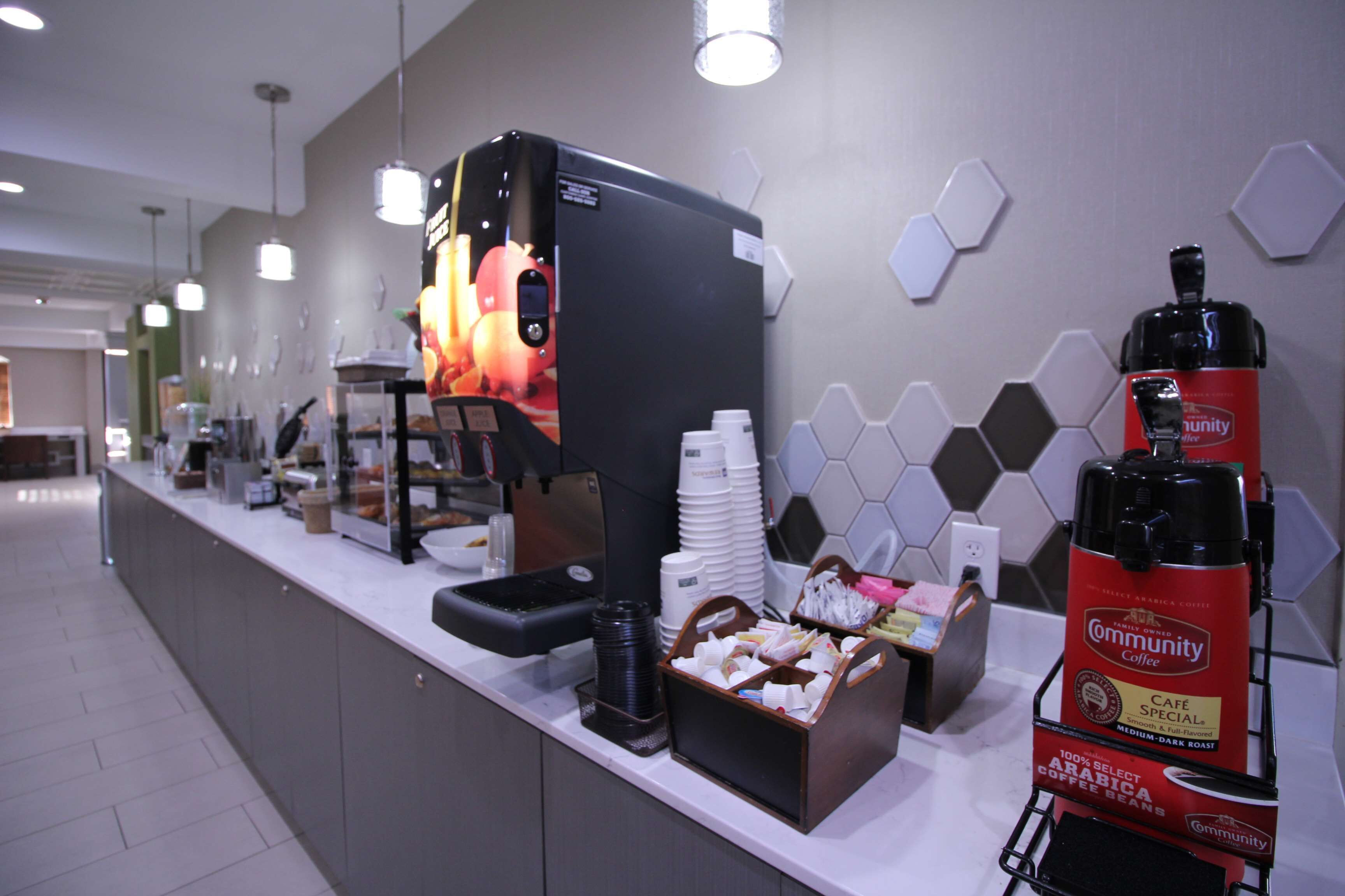 Una estación de café con cafetera, tazas y dispensador de café.
