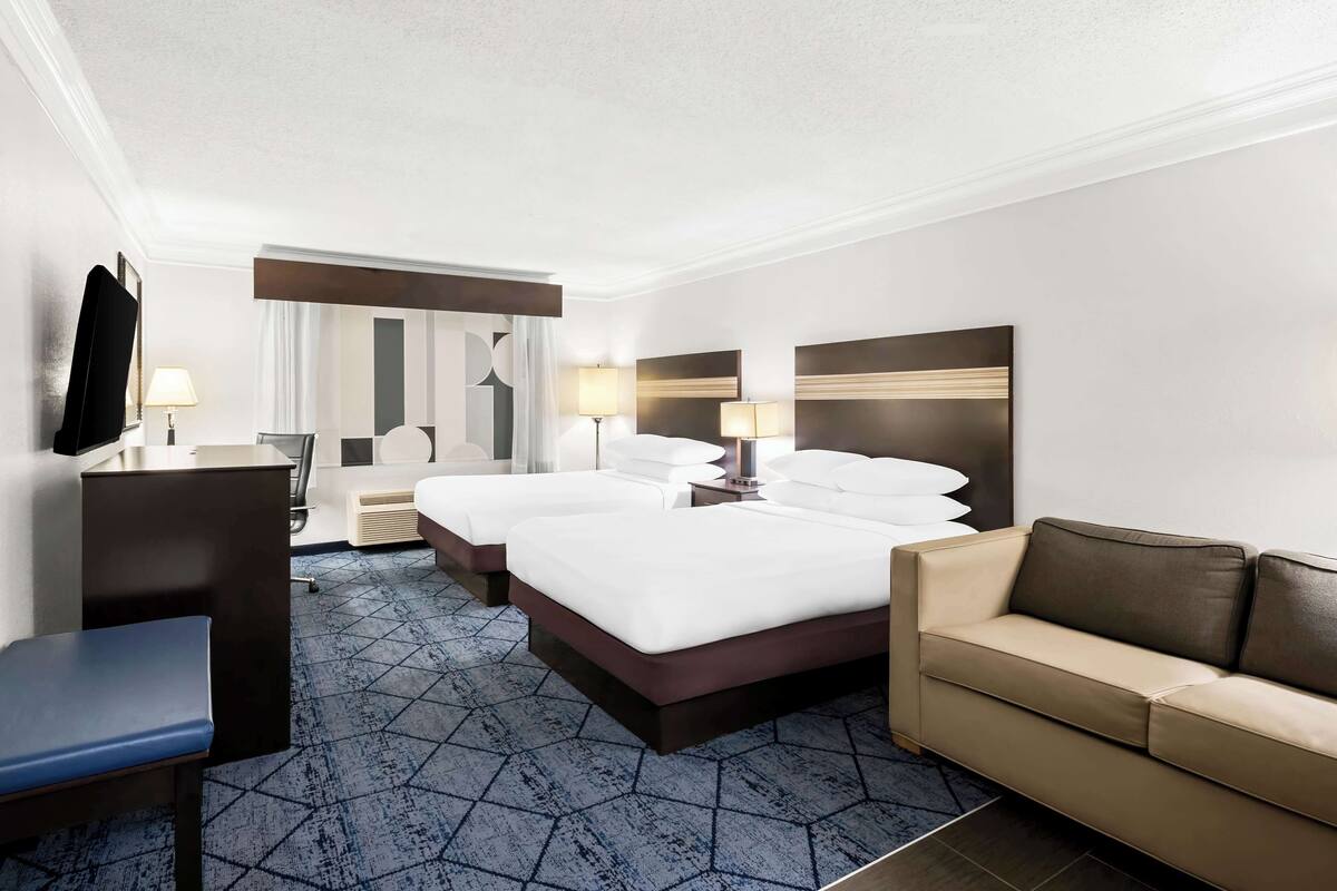 A hotel room with a large bed, a sofa, a desk, and a TV.