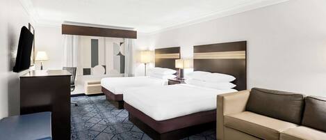 Habitación de hotel con una cama grande, un sofá, un escritorio y un televisor.