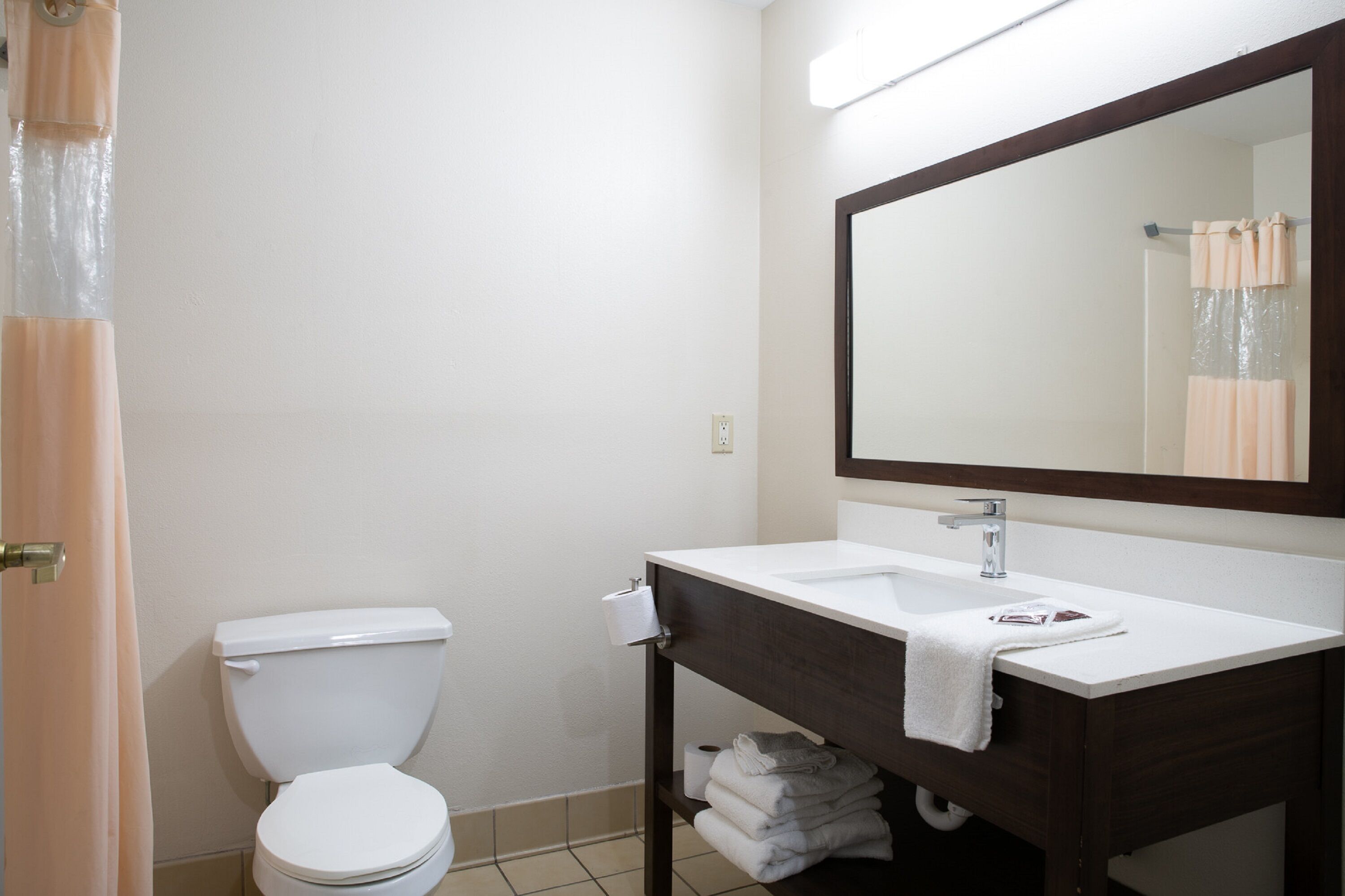 A bathroom with a white toilet, a sink with a mirror above it, and a towel rack.