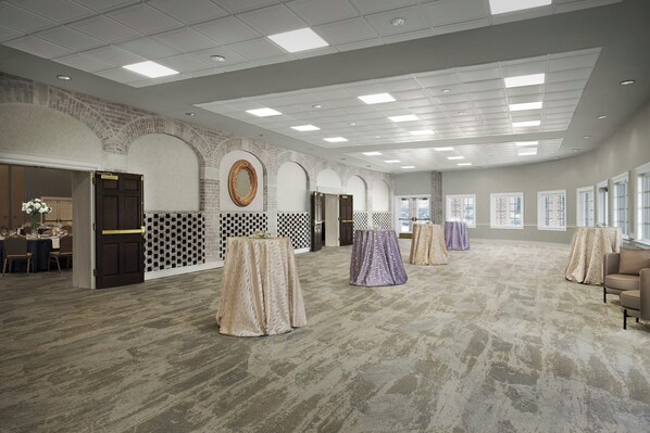A spacious hotel lobby with a high ceiling, patterned walls, and a carpeted floor. - Virginia Crossings Hotel (Glen Allen)